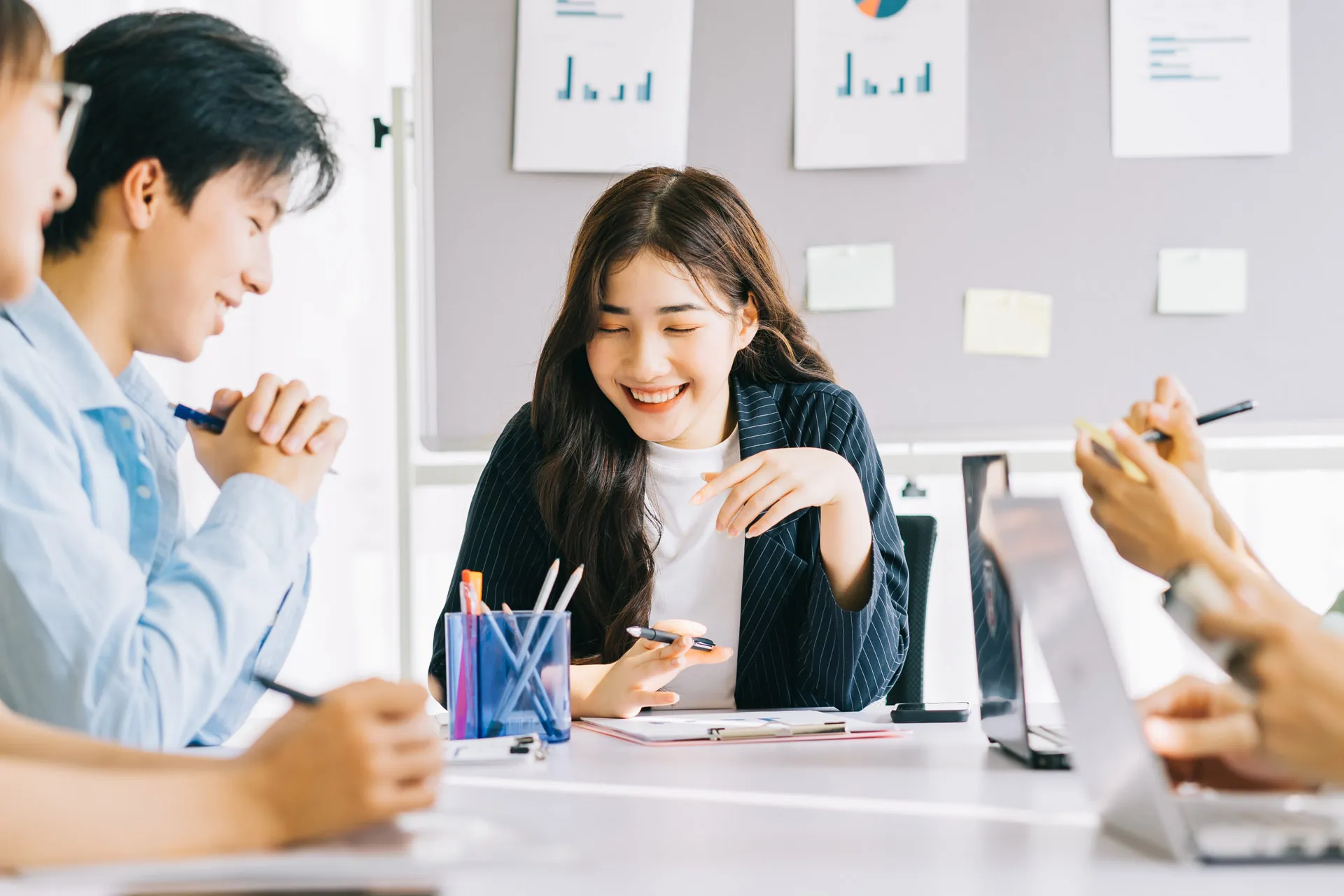 Asian business professionals discussing work at a table in a modern office setting.