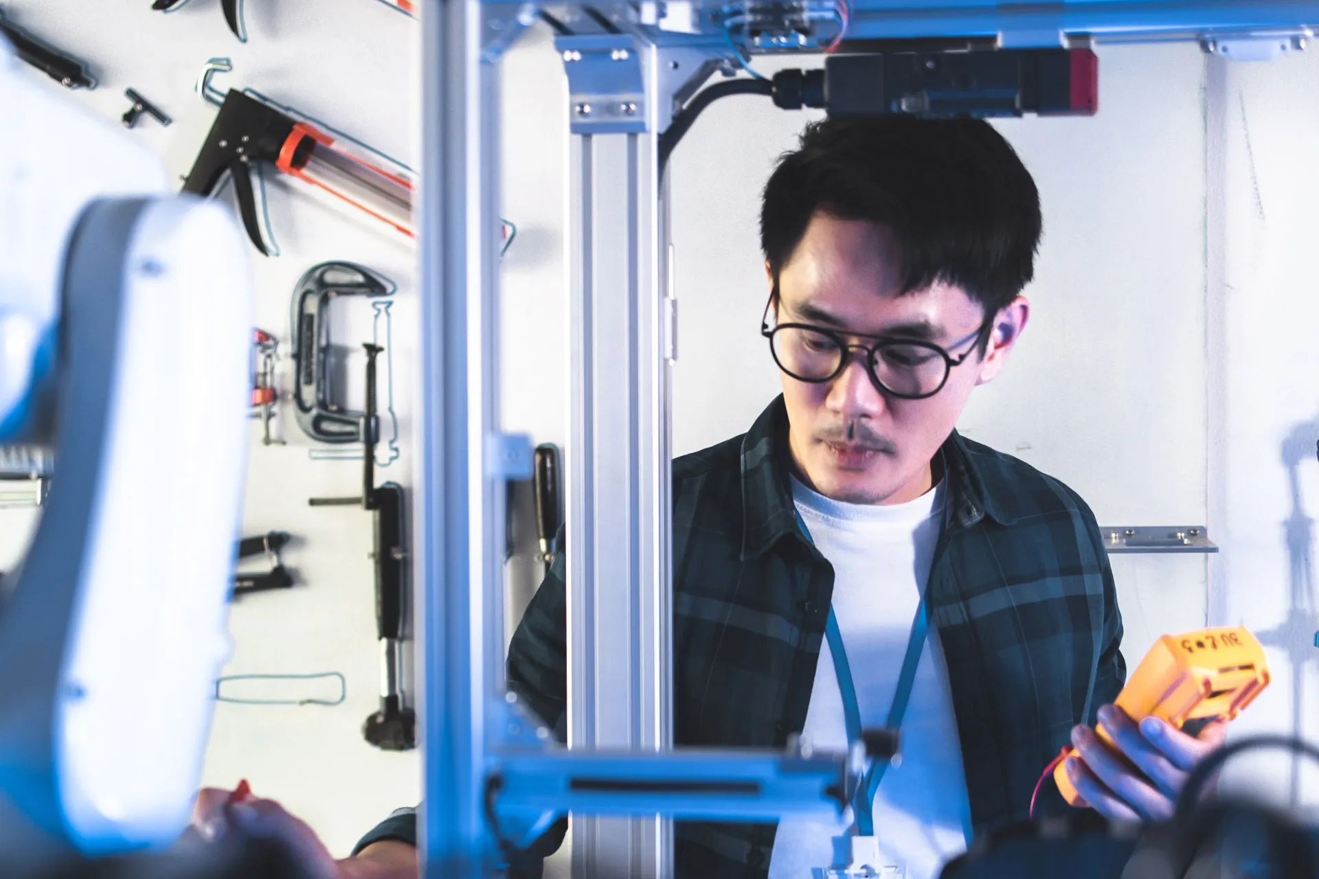 A man in glasses working carefully on a machine in a workshop.