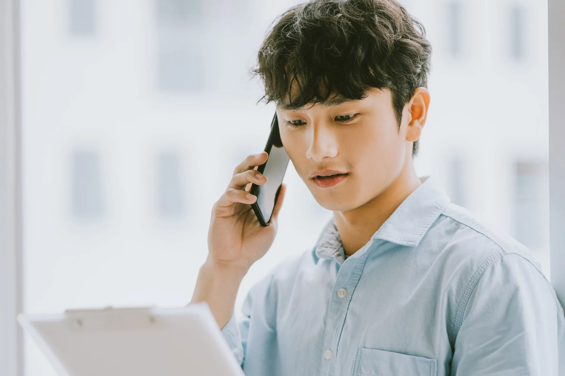  A man multitasking with a phone call and tablet in hand, displaying focus and efficiency.